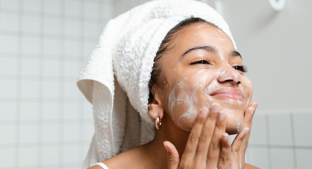 A smiling woman in a white towel finishing her cleanse